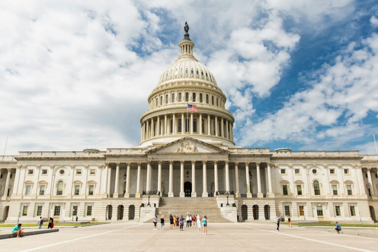 The United States Capitol building in Washington, DC under a blue sky.
